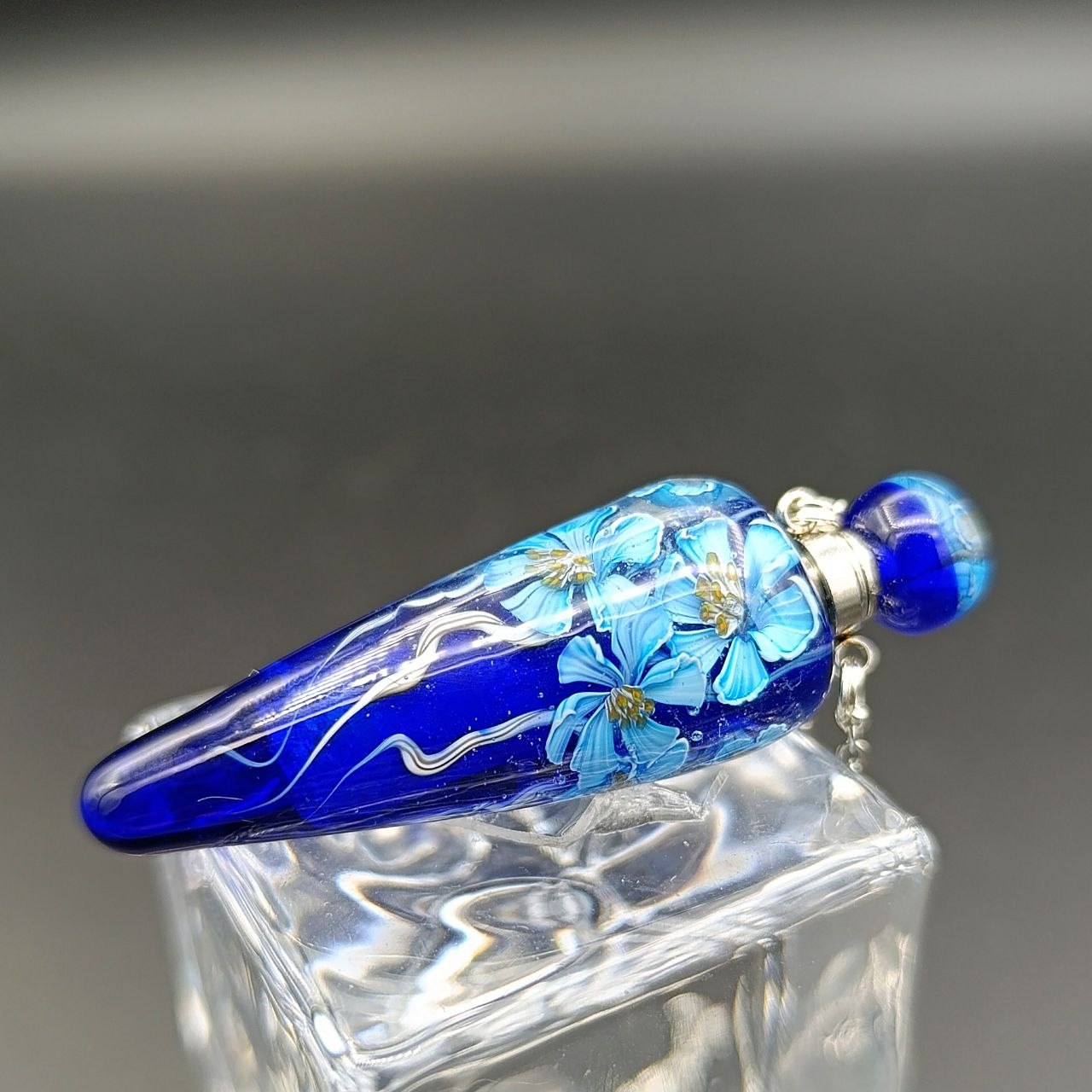 blaue Fiole aus Glas mit weißen Blumen